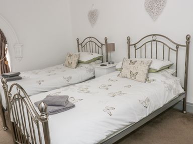 A bedroom with two metal beds and butterfly patterned bedding at Capel Bryn Bachau in Chwilog near Criccieth