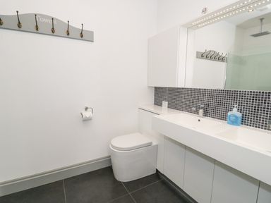 A bathroom with a toilet sink and mirror with hooks on the wall at Capel Bryn Bachau Chwilog near Criccieth