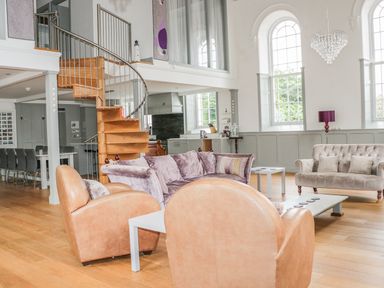 A living room with leather armchairs a purple sofa a spiral staircase and large windows at Capel Bryn Bachau Chwilog near Criccieth