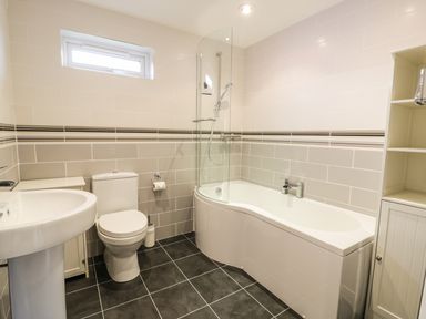 A bathroom with a toilet sink bathtub shower and shelving at Nant Y Felin Lodge in Aberdaron