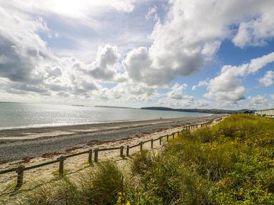 A coastal beach view with sand, sea, dunes, and clouds at Apartment 3 Marian Y Mor in Pwllheli