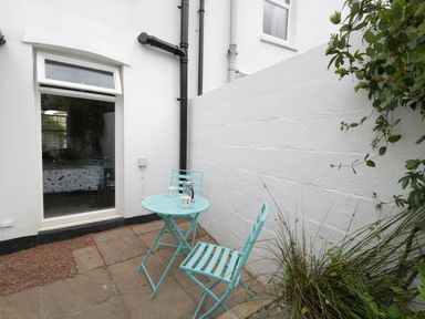 A small outdoor patio with a turquoise table and two chairs next to a white building at No 9 Watchet