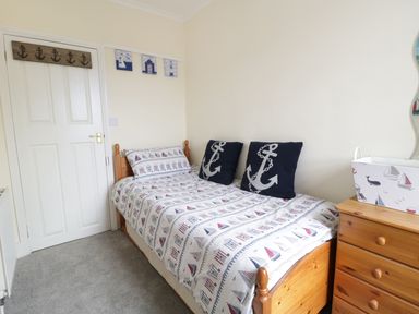 A bedroom with a single bed and dresser with nautical themed decor at No 9 in Watchet