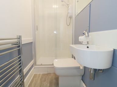 A bathroom with a shower area sink toilet and towel radiator at No 9 in Watchet