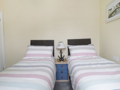 A bedroom with two single beds a blue nightstand and a lamp at No 9 Watchet