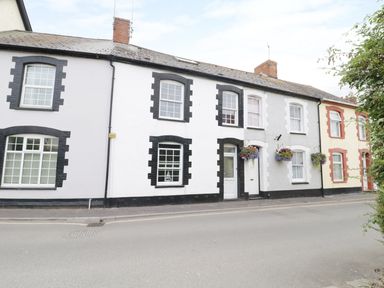 A row of terraced houses with hanging flower baskets along a street at No 9 in Watchet