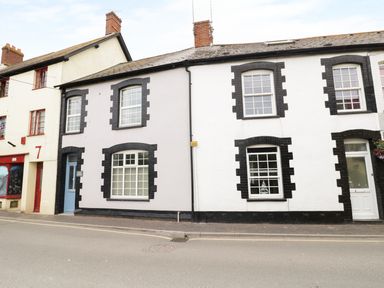 A street view of two attached houses with black window frames and doors at No 9 Watchet