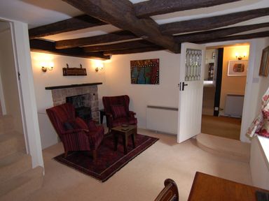 A sitting room with two armchairs and a small table on a rug near a fireplace at Appletree Cottage in Higher Brimley near Bovey Tracey