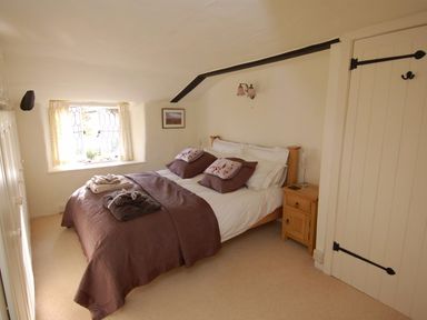 A bedroom with a double bed pillows folded towels bedside table and a window at Appletree Cottage in Higher Brimley near Bovey Tracey