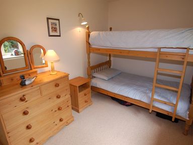 A bedroom with bunk beds a wooden dresser with a lamp and mirror at The Coach House in Ugborough