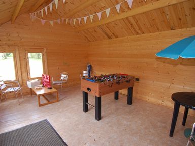 An indoor wooden recreational room with a foosball table chairs and a table with a Connect Four game at The Coach House in Ugborough