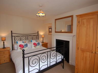 A bedroom with a metal bed frame two wooden bedside tables lamps and a wooden wardrobe at Jordan House in Boscastle