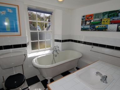 A bathroom with a clawfoot bathtub toilet and sink with tiled countertop at Jordan House in Boscastle