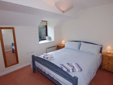 A bedroom with a double bed and two bedside tables with lamps at Pine Cottage in Maenporth