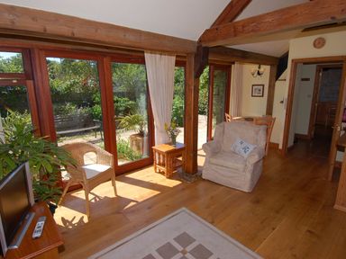 A living room with wooden beams glass doors and armchairs at Sunnyside in Staple Fitzpaine