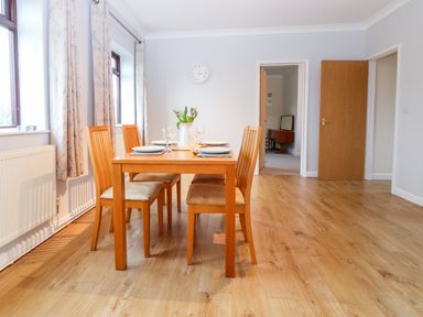 A dining room with a wooden table set for four and wooden chairs at Little Waycroft in Dawlish