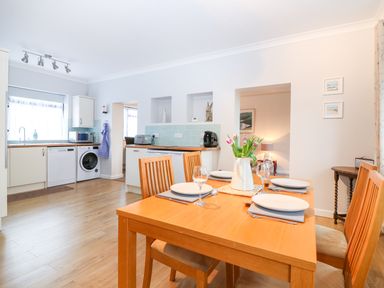 A kitchen and dining area with a wooden table set for four and kitchen appliances at Little Waycroft in Dawlish