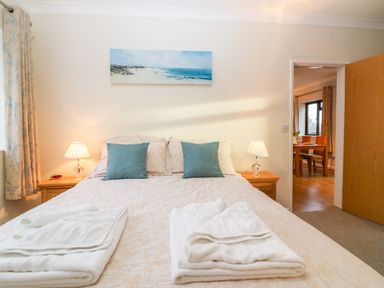 A bedroom with a double bed with folded towels and two bedside tables with lamps at Little Waycroft in Dawlish