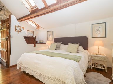 A bedroom with a large bed two bedside tables lamps and framed pictures on walls at The Granary in Edington near Street and Glastonbury