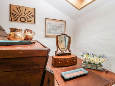 A wooden dresser with a mirror jugs and flowers on top at The Granary in Edington near Street and Glastonbury