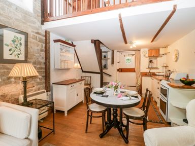 A kitchen and dining area with a small round table set for four and wooden beams on the ceiling at The Granary Edington near Street and Glastonbury