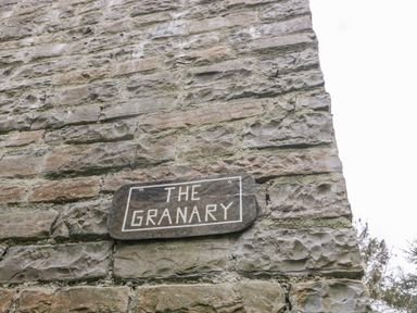 A stone wall with a wooden sign that reads The Granary at The Granary in Edington near Street and Glastonbury