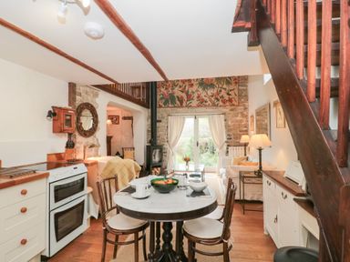 A kitchen and living area with a round dining table and wooden chairs at The Granary in Edington near Street and Glastonbury