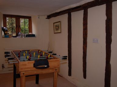 A room with a foosball table near a window and exposed wooden beams on the wall at Surridge Farmhouse in Waterrow