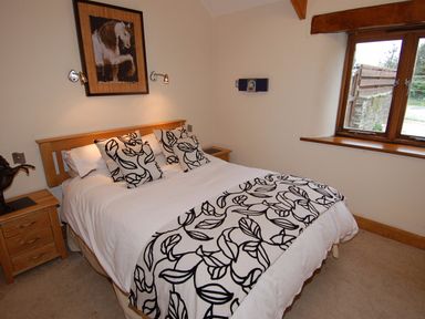 A bedroom with a double bed a wooden headboard and bedside tables with lamps at Hideaway in Tintagel
