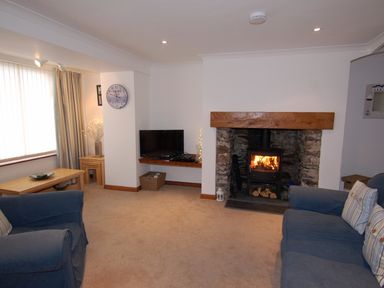A living room with a fireplace tv table and blue sofas at The Keep Pot in Port Isaac