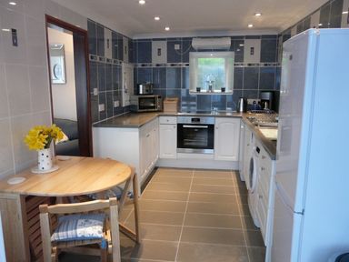 A kitchen with appliances wooden dining table with chairs and flowers at The Keep Pot in Port Isaac