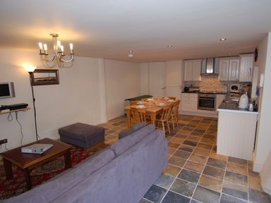 An open living space with a kitchen dining table and sofa at The Barn in Tregoodwell