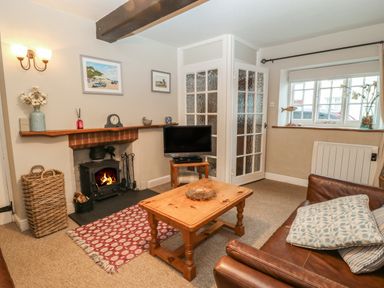 A living room with a fireplace tv and wooden coffee table at Robyn Cottage in Otterton