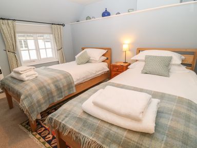 A bedroom with two single beds and a bedside table with a lamp at Robyn Cottage in Otterton