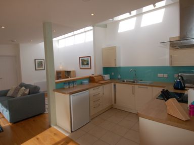A kitchen with wooden countertops and cream cabinets next to a living area with a sofa at Orchard Retreat in Sidmouth