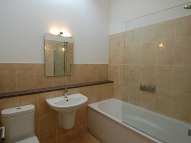 A bathroom with a toilet sink mirror bathtub and tiled walls at Orchard Retreat in Sidmouth