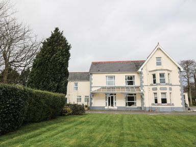 A large two-story house with a lawn and trees at Muriau Park in Caernarfon