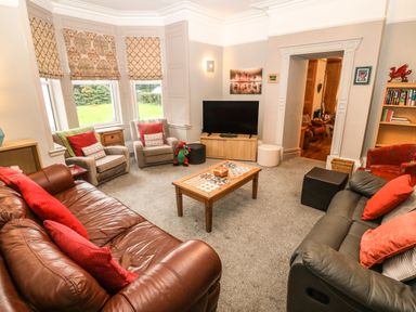 A living room with sofas armchairs a coffee table a television and bookshelves at Muriau Park in Caernarfon