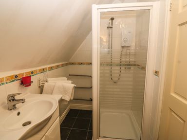 A bathroom with a shower enclosure a sink a towel rack and a sloped ceiling at Muriau Park in Caernarfon