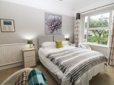 A bedroom with a double bed two bedside tables with lamps an armchair and a large window at Muriau Park in Caernarfon
