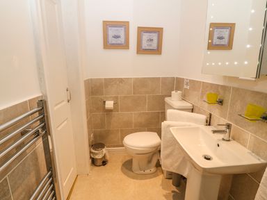 A bathroom with a toilet sink towels and a trash can at Muriau Park in Caernarfon