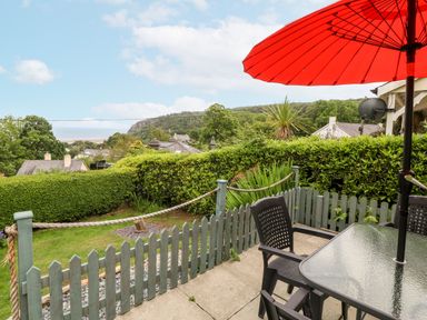A garden with a table and chairs under an umbrella at 2 Argoed Llanbedrog