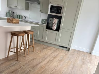 A kitchen with bar stools and cabinets at Storws Tanrallt Llanfachraeth