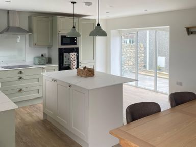 A kitchen with a kitchen island and windows at Storws Tanrallt Llanfachraeth