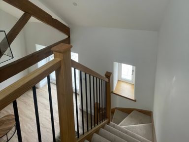 A staircase with wooden beams and a window at Storws Tanrallt Llanfachraeth