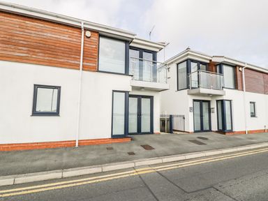 A street view of modern two story buildings with glass balconies and large windows at 7 Marina View in Pwllheli