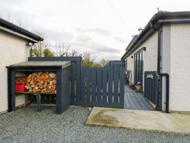An outdoor area with wood storage and a fence at Hafod Wen Pentraeth