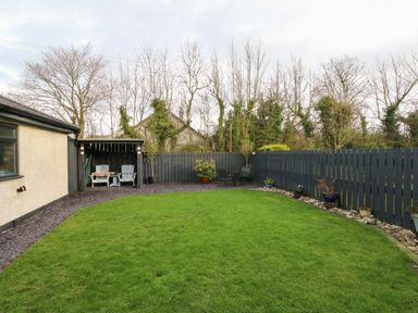 A garden with grass and seating area at Hafod Wen Pentraeth
