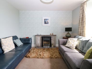 A living room with two sofas a fireplace a lamp and a rug at Trefollwyn Mawr in Abersoch