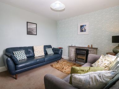 A living room with two sofas a fireplace and framed pictures on the wall at Trefollwyn Mawr in Abersoch